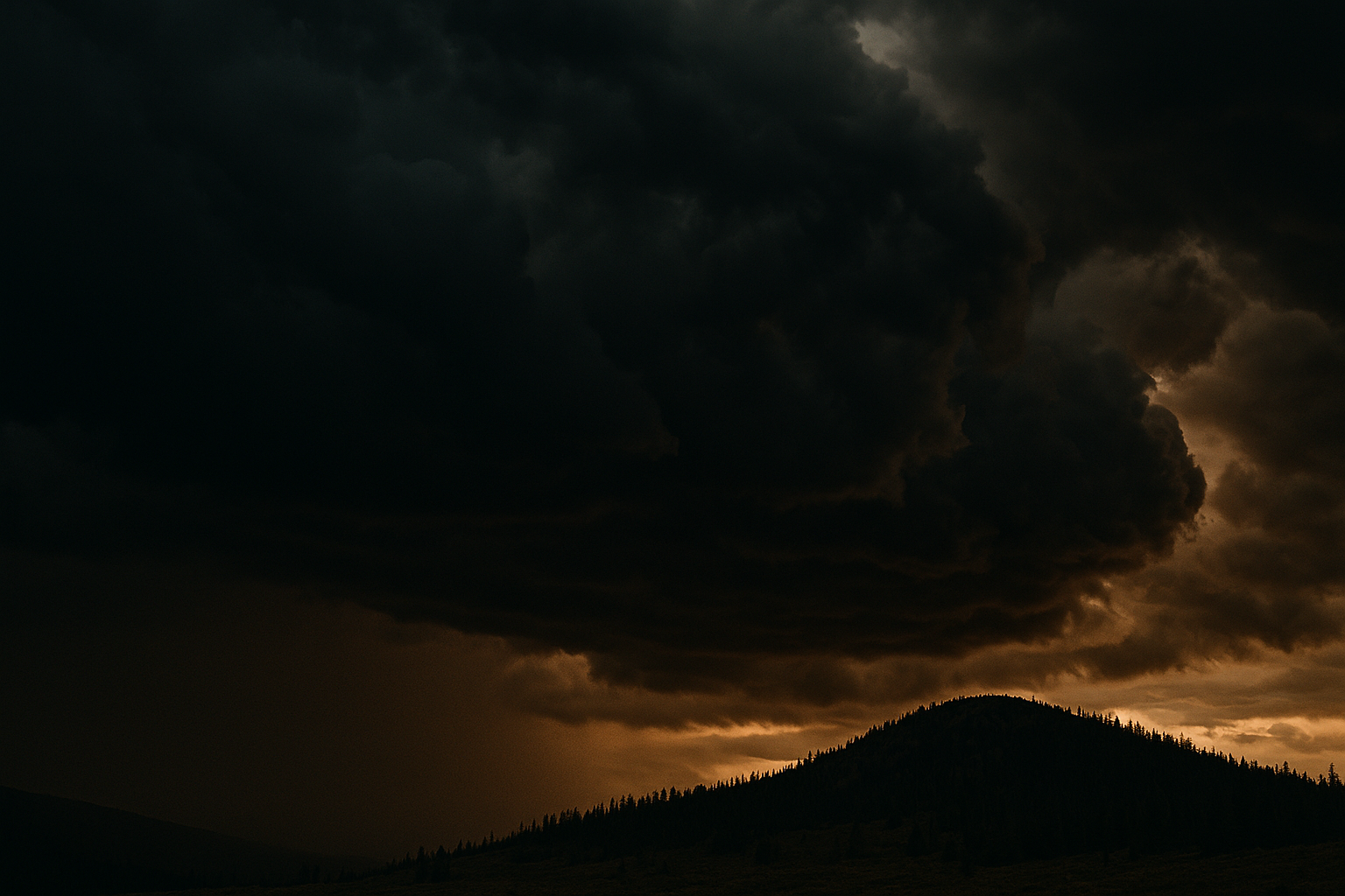 Wide shot of darkening storm clouds building over a distant ridgeline, dramatic natural light, dark and grounded tones, illustrating signs bad weather is coming.